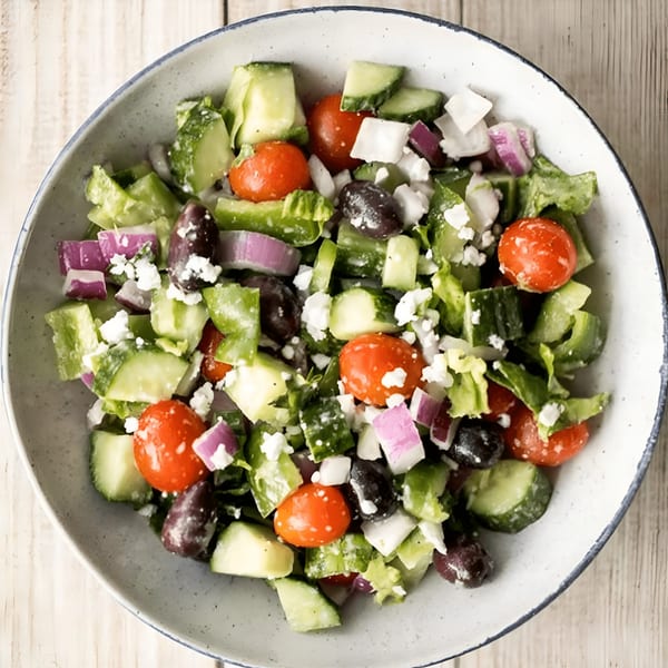 Close-up of a Greek salad with tomatoes, cucumbers, olives, red onion, and feta cheese.